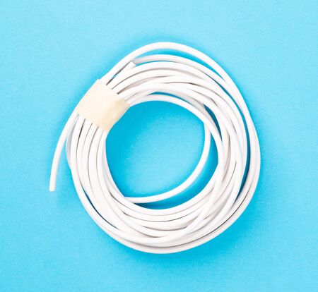 Rolled-up electrical cord isolated on a blue background