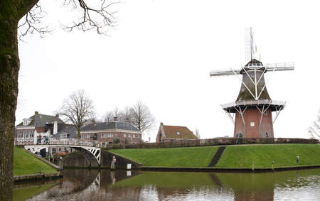 Dokkum, the Netherlands on December 26, 2019: Canal and windmill on fortifications of fortified town of Dokkum, Friesland, Netherlandsのeditorial素材