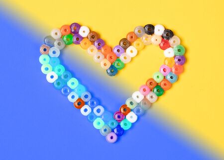 Heart from round plastic parts, isolated on blue and yellow