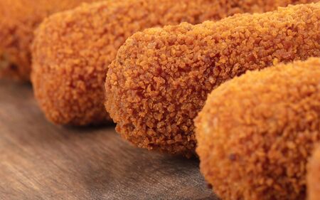 Brown crusty dutch kroketten on a serving tray, isolated on a white background