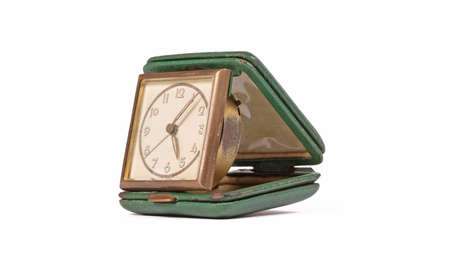 Old green folding travel alarm clock on white background