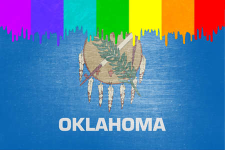 Paint (in the colors of the rainbow flag) is dripping over the state flag of Oklahomaの写真素材