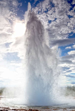 Eruption of Strokkur Geyser against morning sun in Icelandの写真素材
