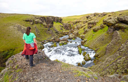 Woman watching the Skoga river before the Skogafoss waterfall, Icelandの写真素材