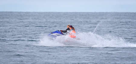 Husavik, Iceland on August 2, 2021: Tourist with guide on a jetski, trying spot large whales