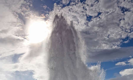 Eruption of Strokkur Geyser against morning sun in Icelandの写真素材
