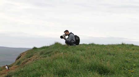 Man photographing a puffin colony in the north of Iceland