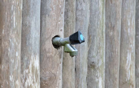 Outside water tap in a wooden wall, selective focusの写真素材