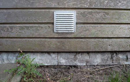 Metal ventilation grille in a wooden wallの写真素材