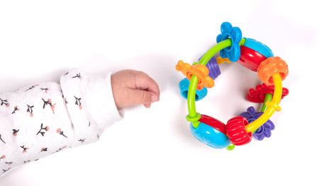Baby hand (female) reaching for a toy, isolated on white background