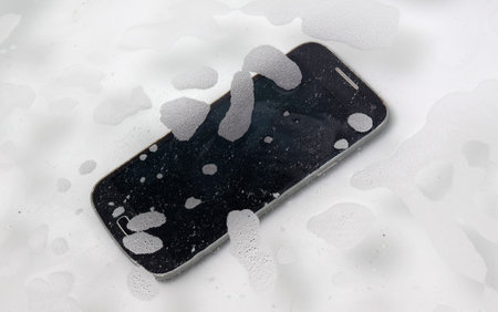 Black smartphone is lying in the water - Fallen in the bathtubの写真素材