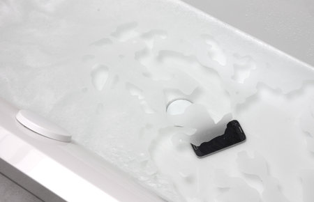 Black smartphone is lying in the water - Fallen in the bathtubの写真素材