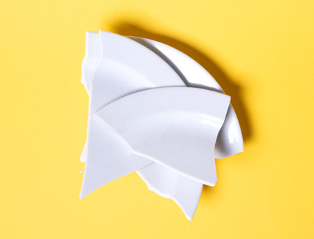Broken white plate on a solid yellow backgroundの写真素材