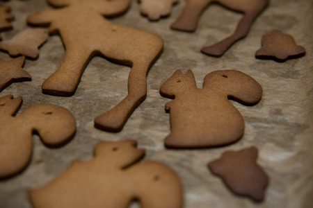 different shapes cutted out from a layer of gingerbread dough and baked