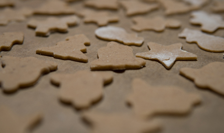 different christmas shapes cutted out from a layer of gingerbread dough on baking paperの写真素材