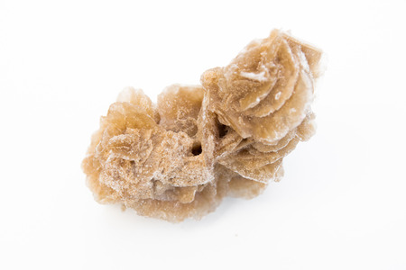 extreme close up of Desert rose gypsum mineral isolated over white background with sand grains