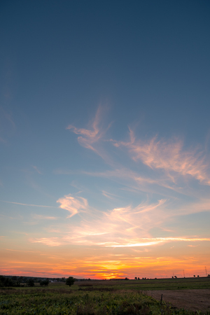 scenic rural landscape of fields during sunset with colorful sky and cirro stratus cloudsの写真素材