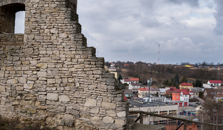 view on old walls of a castle syanding on a hill over small townの写真素材