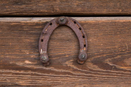 old and rusty horseshoe hanging on a woodden wallの写真素材