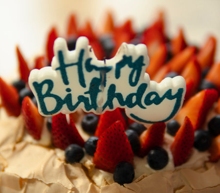 happy birthday candle on a cake with strawberries and blueberriesの写真素材