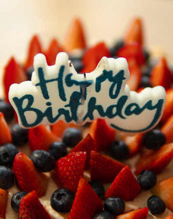 happy birthday candle on a cake with strawberries and blueberriesの写真素材