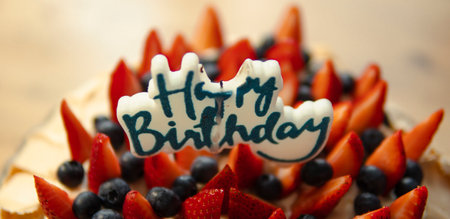 happy birthday candle on a cake with strawberries and blueberriesの写真素材