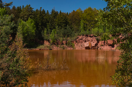 Landscape of an abandoned red sandstone quarry with water filling its bottomの写真素材