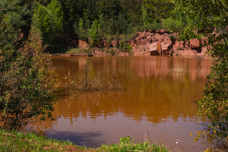 Landscape of an abandoned red sandstone quarry with water filling its bottomの写真素材