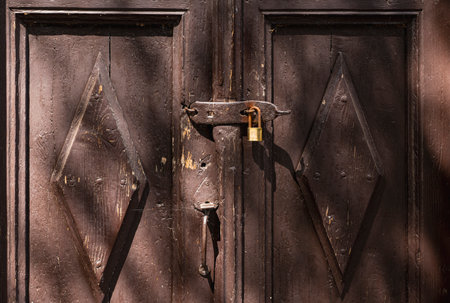 close-up of an old wooden door locked with a metal padlock
