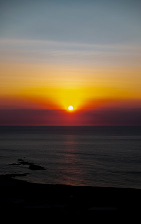 The sun at orange sunset just above the surface of the seaの写真素材