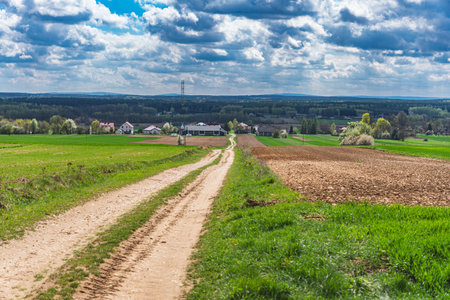 Landscape showing village and fields at the beginning of spring with cumulus cloudsの写真素材