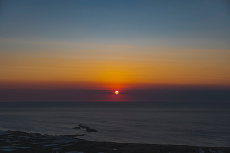 The sun at orange sunset just above the surface of the seaの写真素材