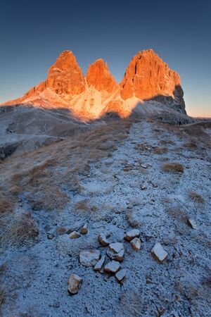Amazing view of famous Dolomite peaks glowing in beautiful golden evening light at sunset in winter time, first snow. Trentino Alto Adige, Dolomites Mountains, South Tyrol, Italy, Europe. Beautiful landscape backgrounの写真素材
