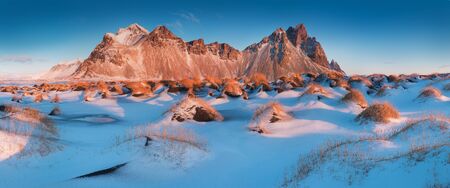 Cracks on the surface of the blue ice. Frozen lake in winter mountains. Blue sky with sun light and high mountains on background. Beautiful winter panorama.の写真素材