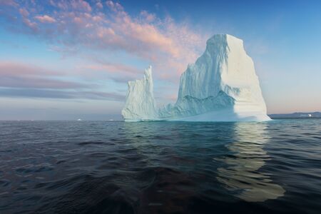 Iceberg at sunset. Nature and landscapes of Greenland. Disko bay. West Greenland. Summer Midnight Sun and icebergs. Big blue ice in icefjord. Affected by climate change and global warming.の写真素材