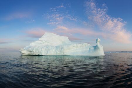 Iceberg at sunset. Nature and landscapes of Greenland. Disko bay. West Greenland. Summer Midnight Sun and icebergs. Big blue ice in icefjord. Affected by climate change and global warming.の写真素材