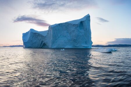 Iceberg at sunset. Nature and landscapes of Greenland. Disko bay. West Greenland. Summer Midnight Sun and icebergs. Big blue ice in icefjord. Affected by climate change and global warming.の写真素材