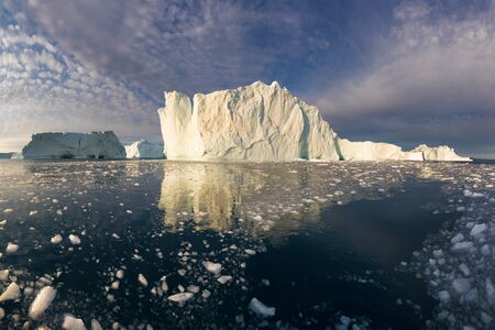 Iceberg at sunset. Nature and landscapes of Greenland. Disko bay. West Greenland. Summer Midnight Sun and icebergs. Big blue ice in icefjord. Affected by climate change and global warming.の写真素材