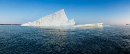 Iceberg at sunset. Nature and landscapes of Greenland. Disko bay. West Greenland. Summer Midnight Sun and icebergs. Big blue ice in icefjord. Affected by climate change and global warming.の写真素材