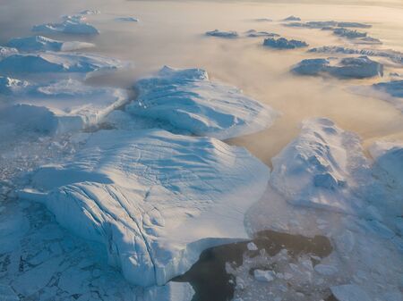 Icebergs drone aerial image - Climate Change and Global Warming. Icebergs from melting glacier in icefjord in Ilulissat, Greenland. Arctic nature ice landscape in UNESCO World Heritage Site.の写真素材