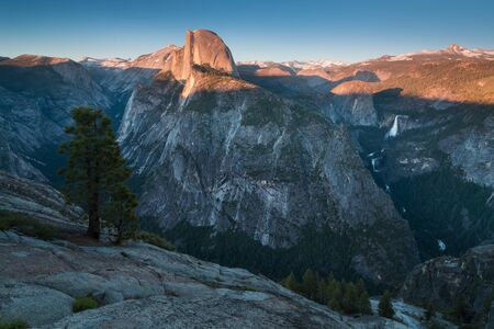 Half Dome and Yosemite Valley in Yosemite National Park during colorful sunset with trees and rocks....