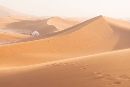 Camp with tent in the desert among sandy dunes. Sunny day in the Sahara during a sand storm in...