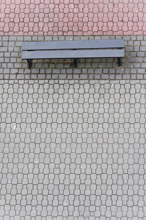 Bench on the red and gray cobblestone streetの写真素材