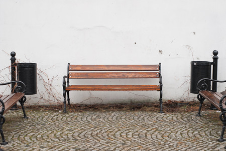 Brown Bench against white wall on cobblestone streetの写真素材