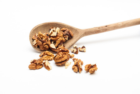 Walnuts on the wooden spoon against white background