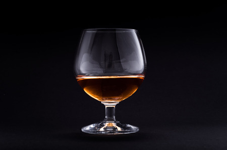 Photo of cognac in glass against black backgroundの写真素材