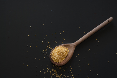 photo of millet on wooden spoon on dark wooden tableの写真素材