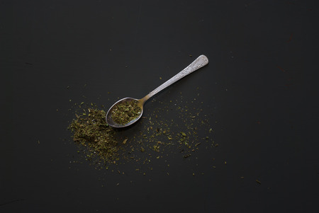 Dried basil on metal teaspoon on dark wooden tableの写真素材