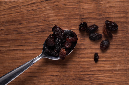 risins photo of on metal spoon on brown wooden tableの写真素材