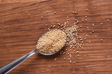 millet photo of on metal spoon on brown wooden tableの写真素材